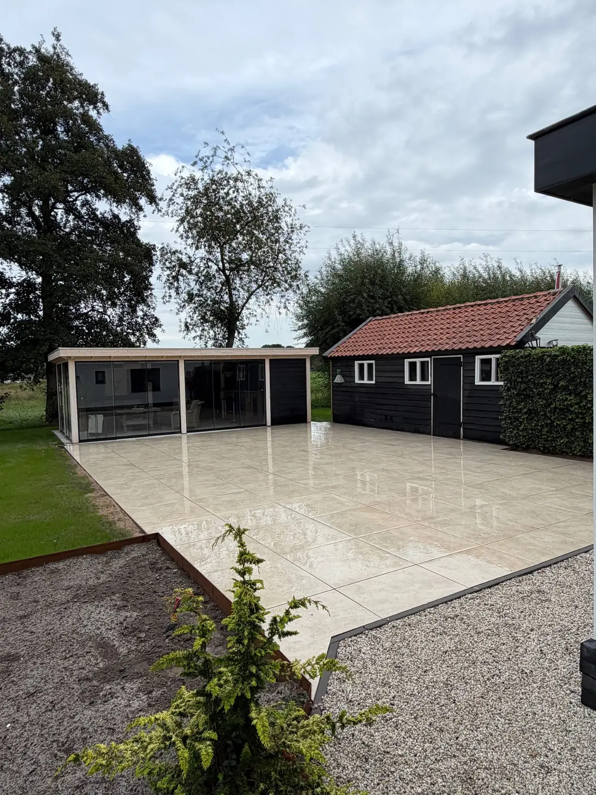 Overzicht van het terras naast gazon en bijgebouw