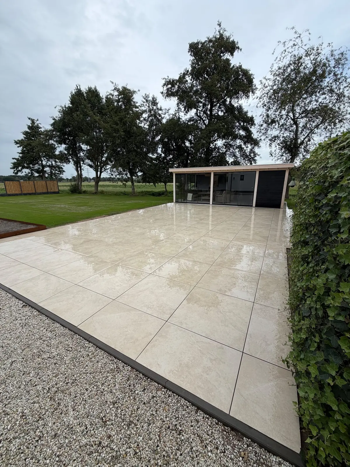 Groot keramisch terras met aansluiting op het gazon en grindpad