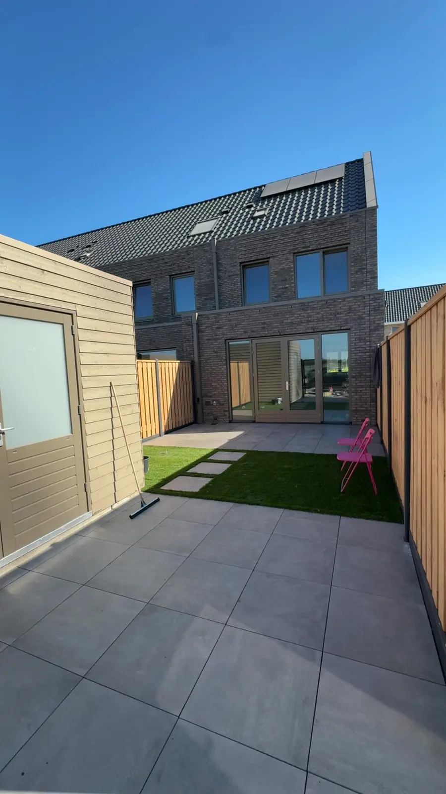 Kunstgras en staptegels tussen terras en achtergevel
