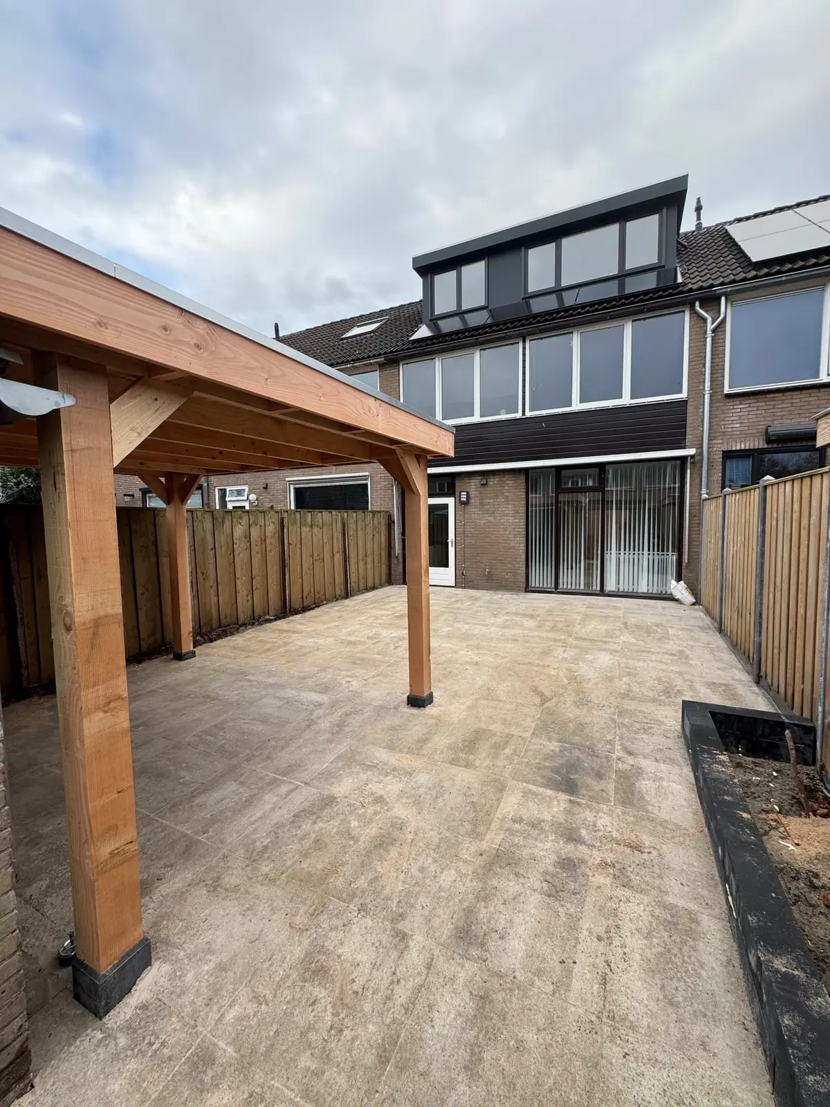 Aansluiting van de bestrating op de woning en houten overkapping