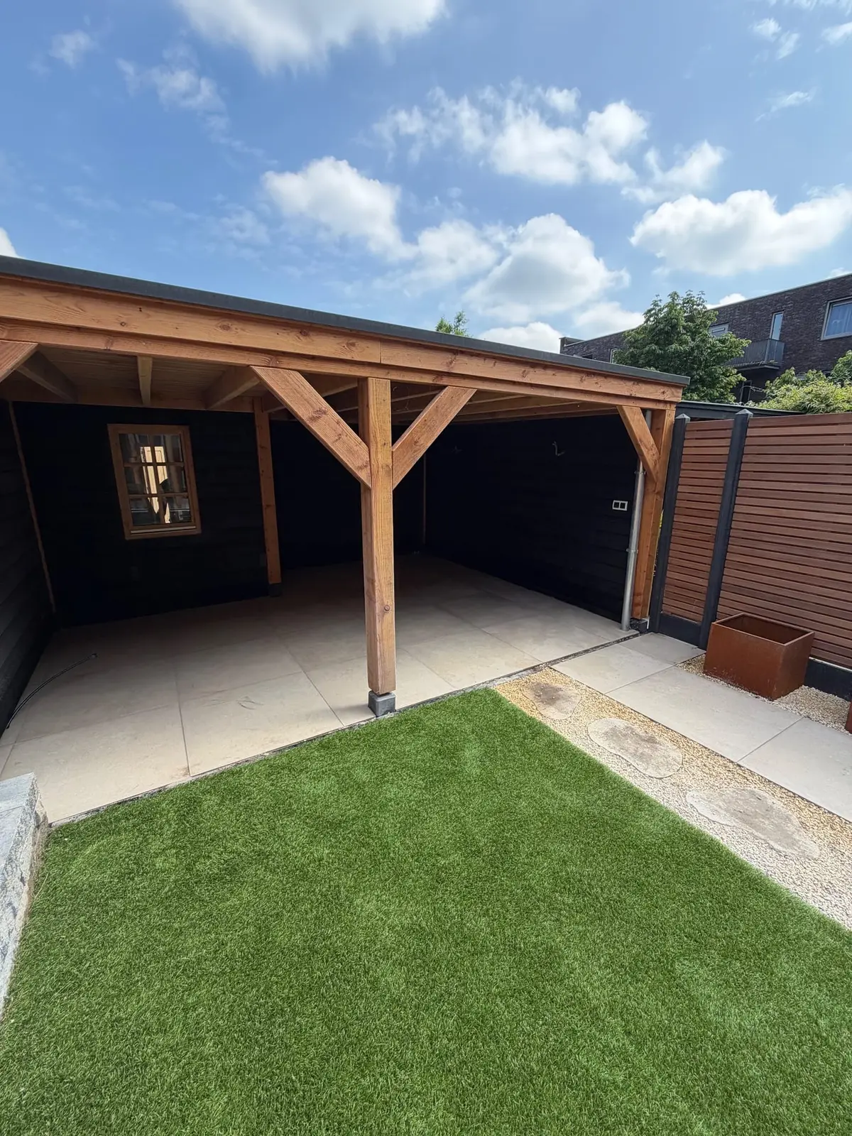 Overkapping aan het einde van de tuin met bestrating en groen vlak
