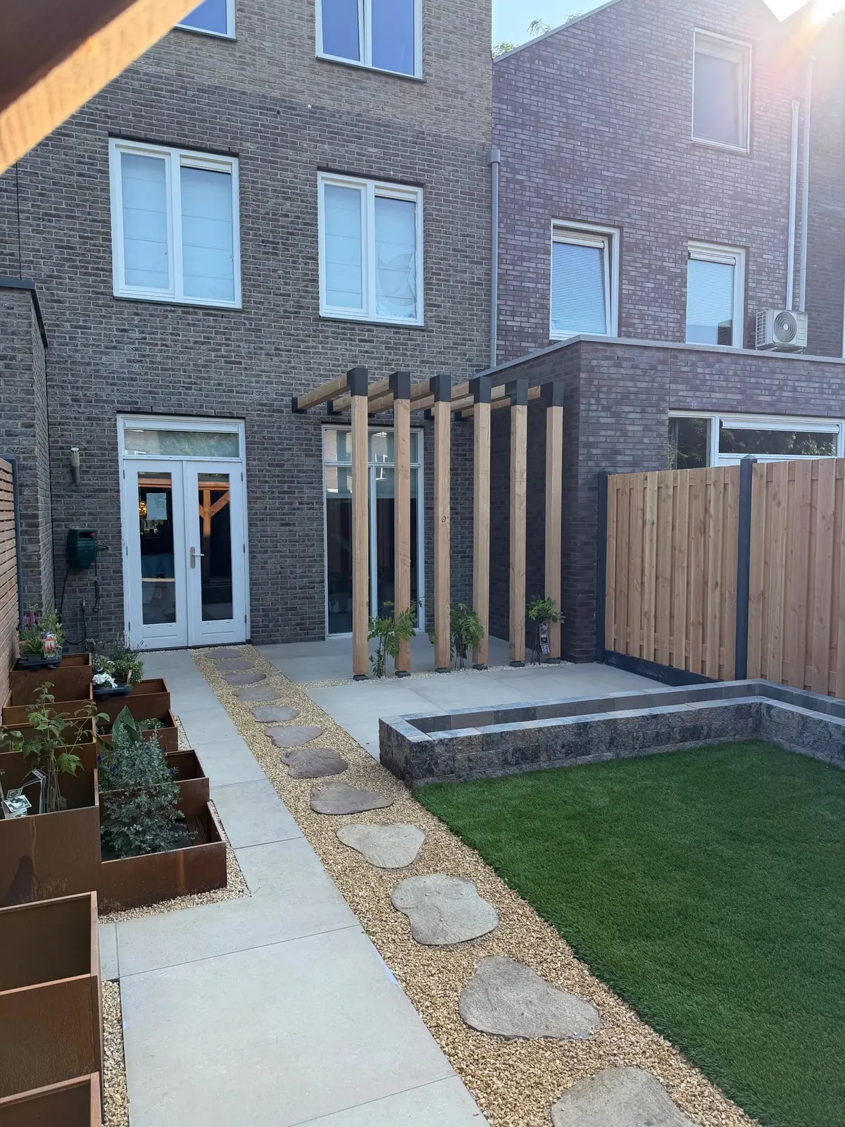 Tuinpad tussen de plantenbakken richting de woning