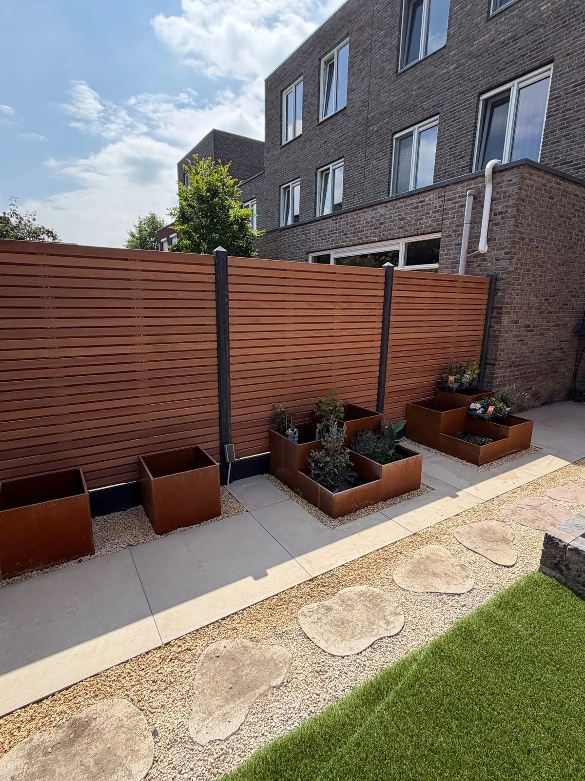 Houten schutting met plantenbakken langs de bestrating
