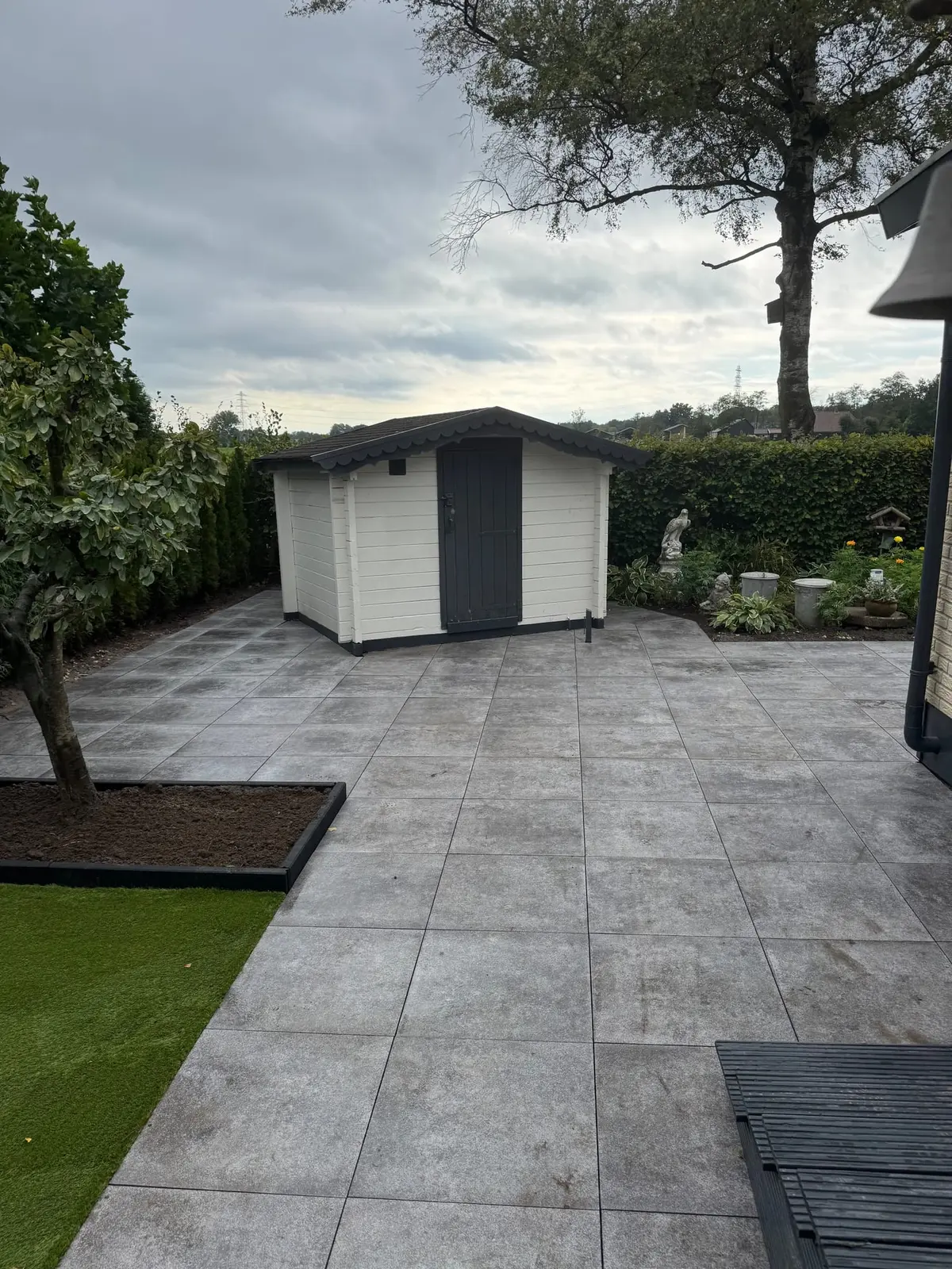 Terras bij de berging met een boom in een uitgespaarde border