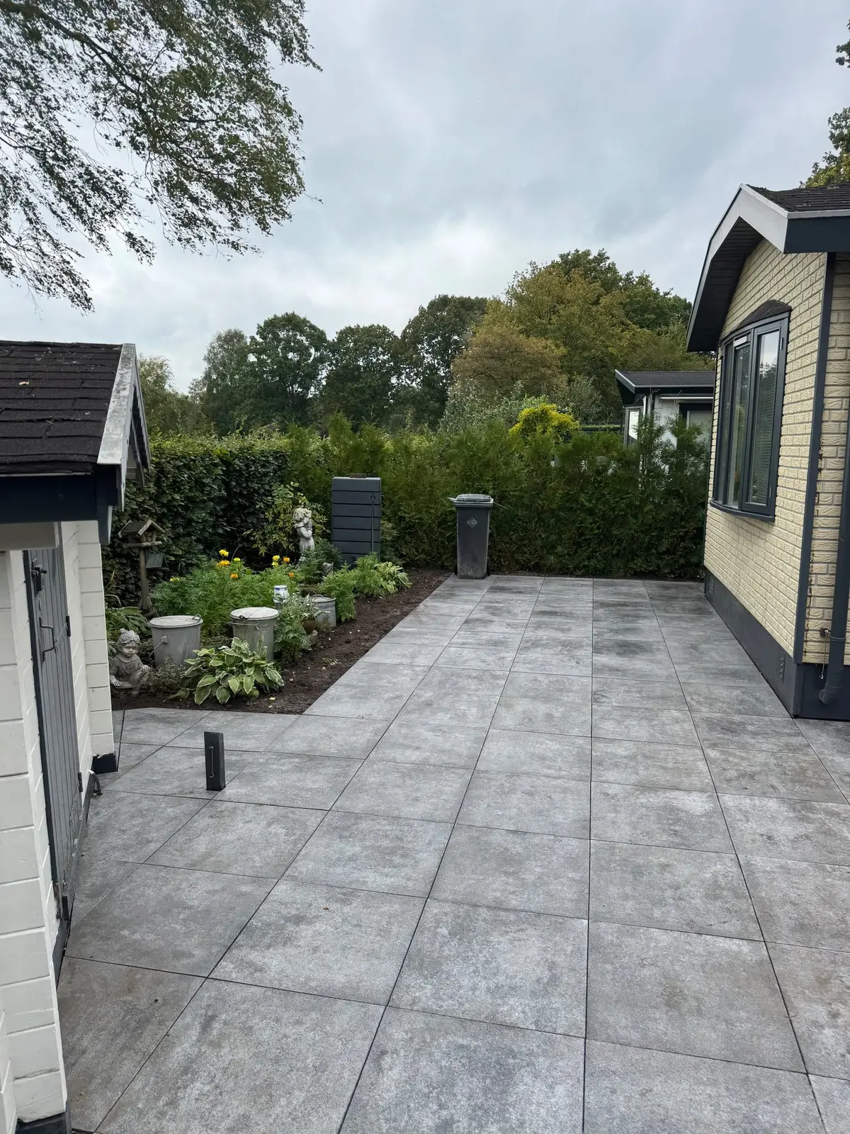 Overzicht van de nieuwe tuin met bestrating, kunstgras en beplanting