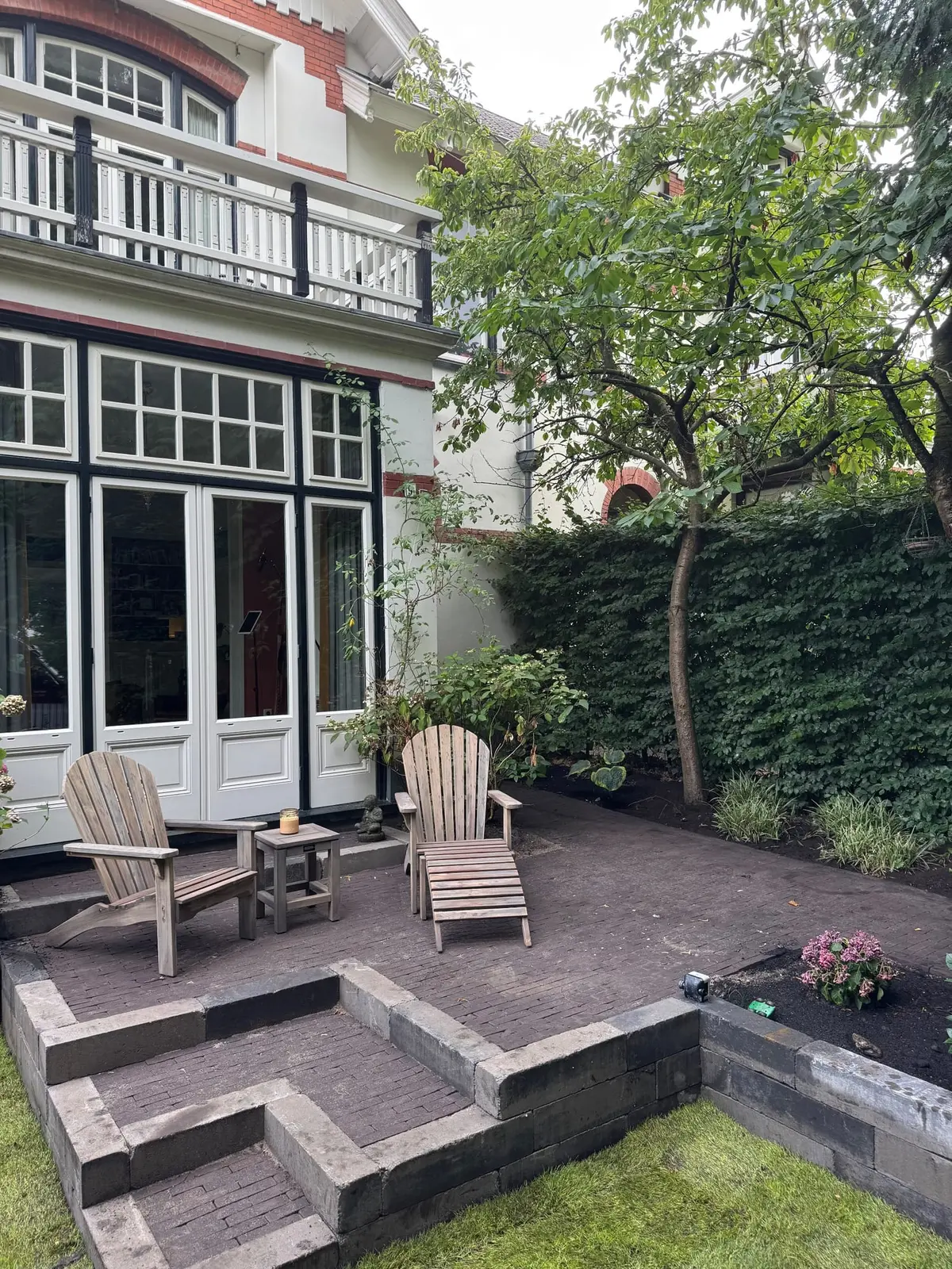 Zitplek op het terras met trap naar het lager gelegen gazon