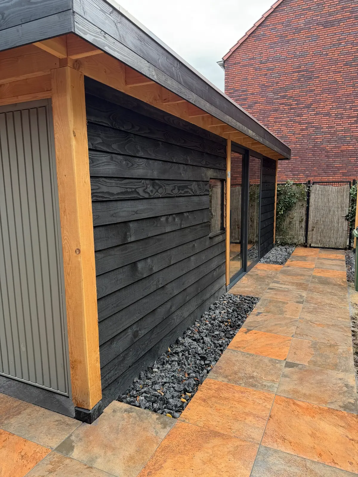 Detail van de houten staander en donkere gevelafwerking