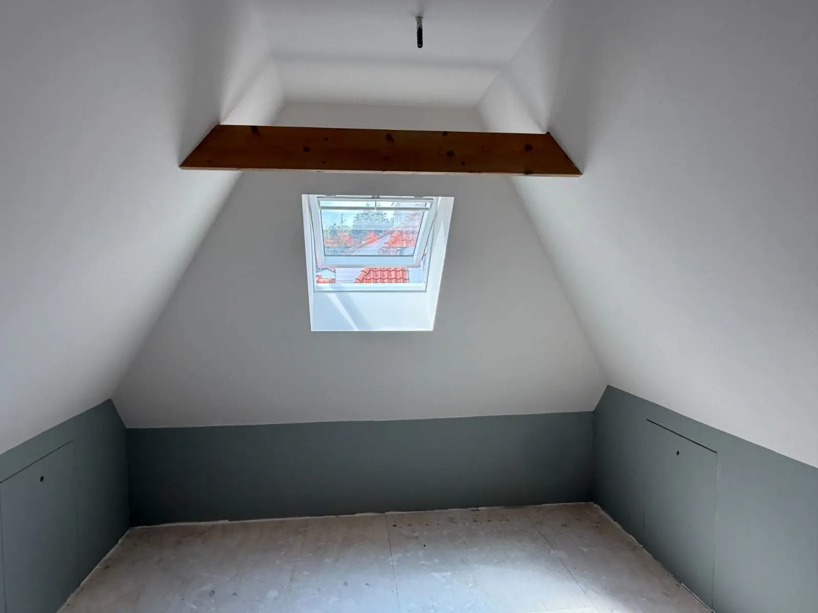Afgewerkte kamer met houten balk en dakraam
