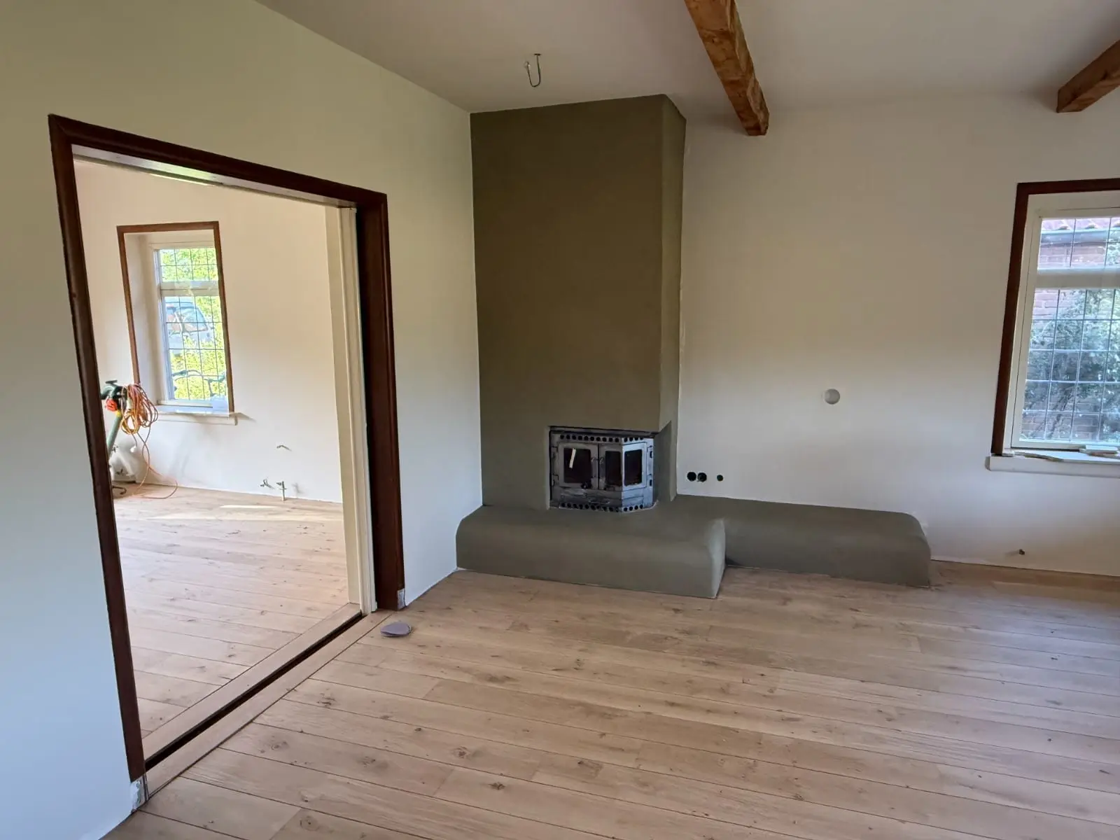 Vernieuwde woonkamer met zichtbare houten balken en schouw