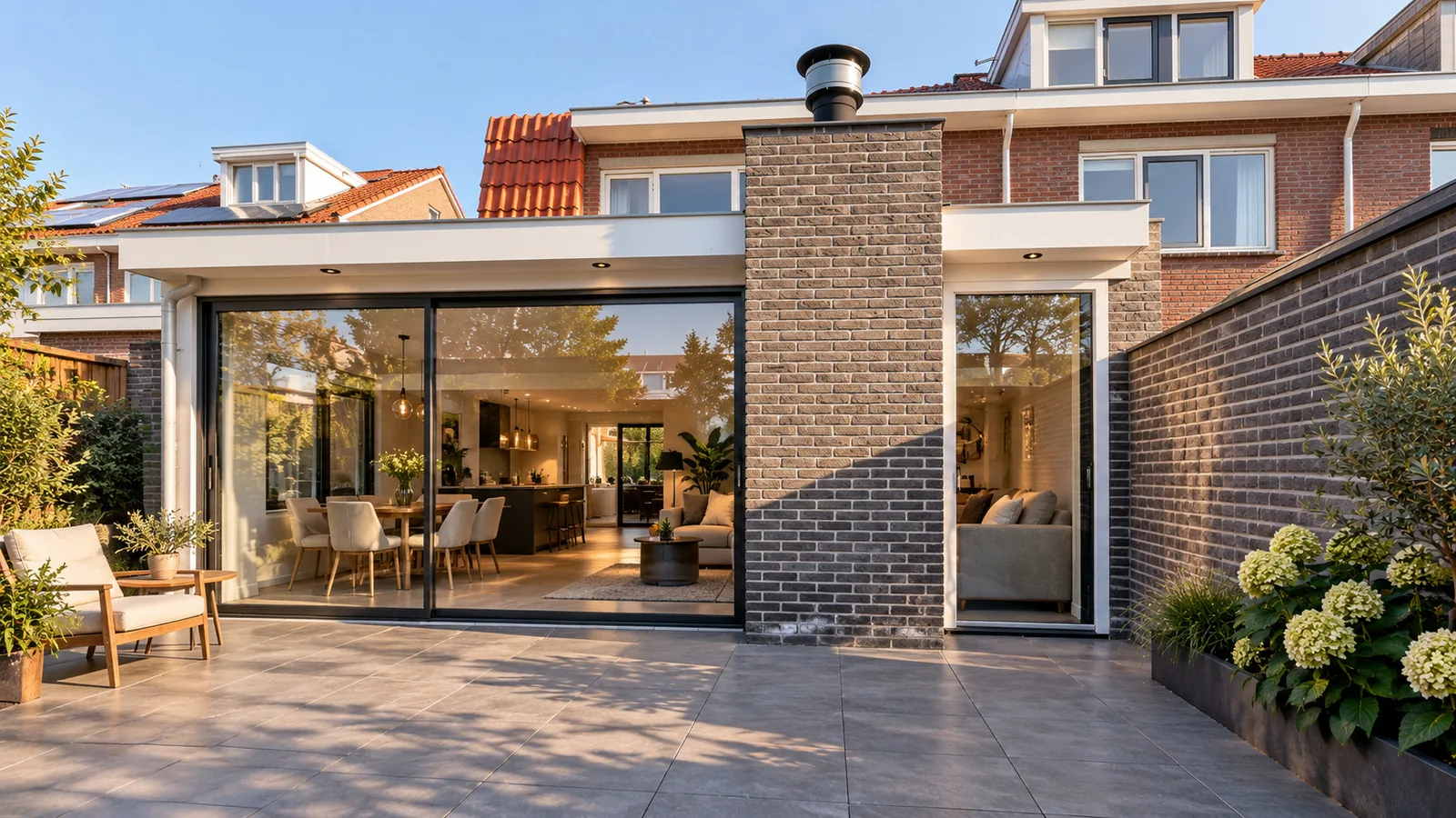 Sfeerbeeld van een gemetselde aanbouw met brede schuifpui en zicht op de leefruimte